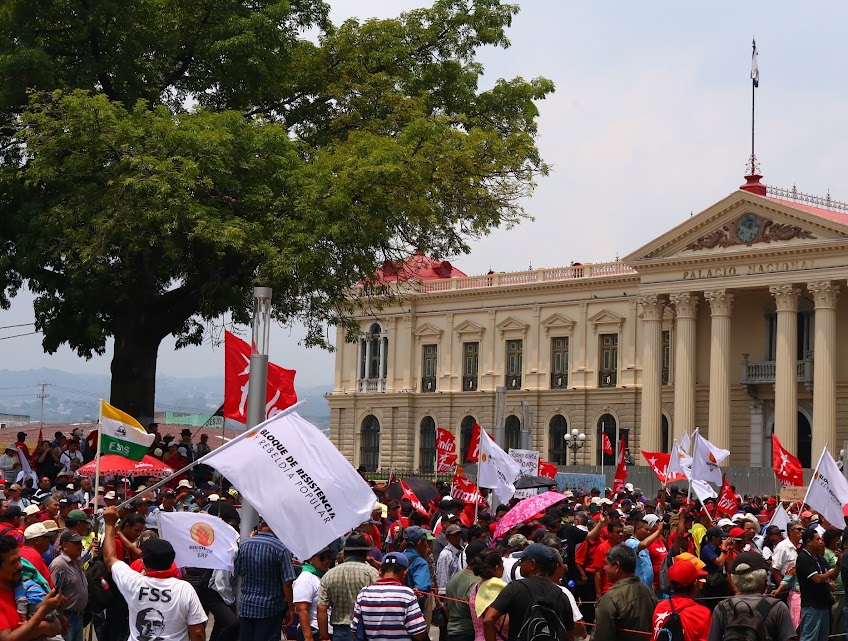 May Day Marcher waves Bloque de Resistencia y Rebeldia flag in front of the National Palace