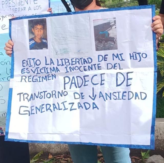 A mother holds a sign that says, in Spanish "I demand my son's release. He is an innocent victim of the regime. He suffers from generalized anxiety disorder."