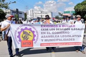 Members of the Fired Workers Movement march with a banner that says "We demand that Bukele stop illegal firings in the government, Legislative Assembly, and municipalities. We demand the immediate instatement of the people who were fired."