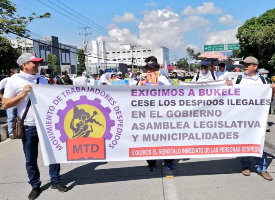 Members of the Fired Workers Movement march with a banner that says "We demand that Bukele stop illegal firings in the government, Legislative Assembly, and municipalities. We demand the immediate instatement of the people who were fired."